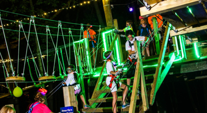 kids climbing ropes course in the dark with neon lights