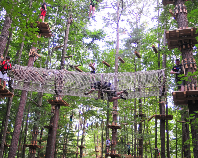 group of people on different tiers of ropes course