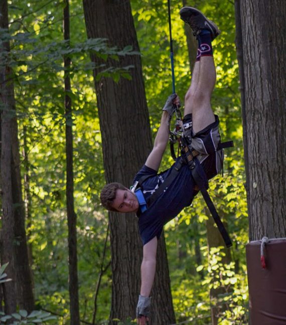 Man hanging vertically from ropes course